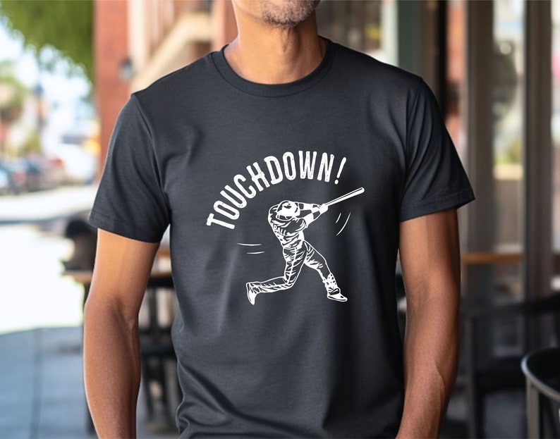 May include: Black t-shirt with a white graphic of a baseball player swinging a bat and the text "TOUCHDOWN!"
