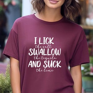 May include: A maroon t-shirt with white text that reads "I lick the salt swallow the tequila and suck the lime".