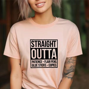 May include: A peach-colored t-shirt with the text "STRAIGHT OUTTA" in a black, bold font, followed by a list of words. The shirt is short-sleeved and has a crew neck.