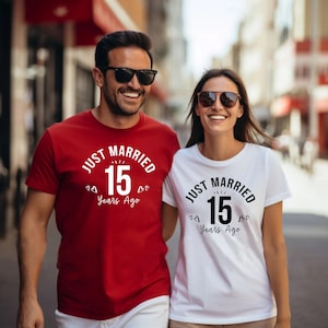 May include: A couple wearing matching t-shirts with the text "JUST MARRIED 15 Years Ago". The man's shirt is red, and the woman's is white. Both shirts have the text in black and white.