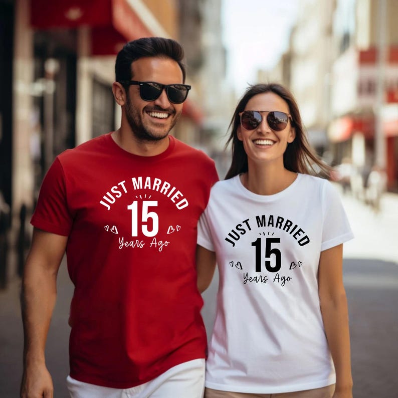 May include: A couple wearing matching t-shirts with the text "JUST MARRIED 15 Years Ago". The man's shirt is red, and the woman's is white. Both shirts have the text in black and white.