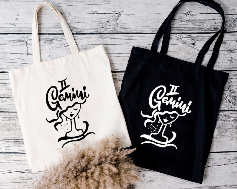 May include: Two tote bags with black and white Gemini zodiac sign designs. The bag on the left is white with black text and design. The bag on the right is black with white text and design.