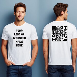 May include: White t-shirt with the text "YOUR LOGO OR BUSINESS NAME HERE" on the front and a QR code on the back. The t-shirt is being modeled by a person wearing blue jeans.