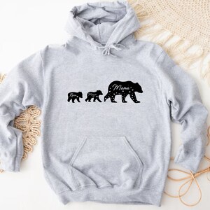 May include: Gray hooded sweatshirt with a black silhouette of three bears walking. The largest bear says "Mama" and the smaller bears say "Rise" and "Mama".
