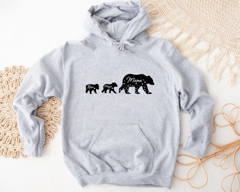 May include: Gray hooded sweatshirt with a black silhouette of three bears walking. The largest bear says "Mama" and the smaller bears say "Rise" and "Mama".