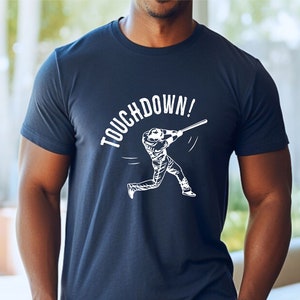 May include: A navy blue t-shirt with a white graphic of a baseball player swinging a bat and the text "TOUCHDOWN!"
