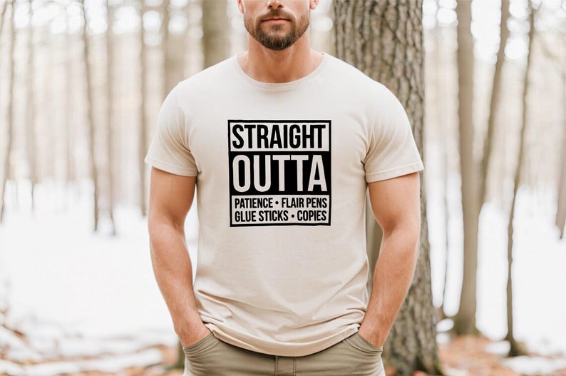 May include: Beige t-shirt with the text "STRAIGHT OUTTA" in a black box, followed by "PATIENCE &bull; FLAIR PENS &bull; GLUE STICKS &bull; COPIES" in a smaller black box. The shirt is short-sleeved.