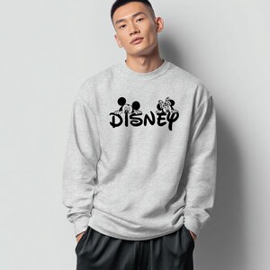 Pu&ograve; includere: Una felpa grigio chiaro con la scritta "DISNEY" in nero, con le sagome di Topolino e Minnie Mouse sopra il testo. La felpa ha un girocollo e maniche lunghe.