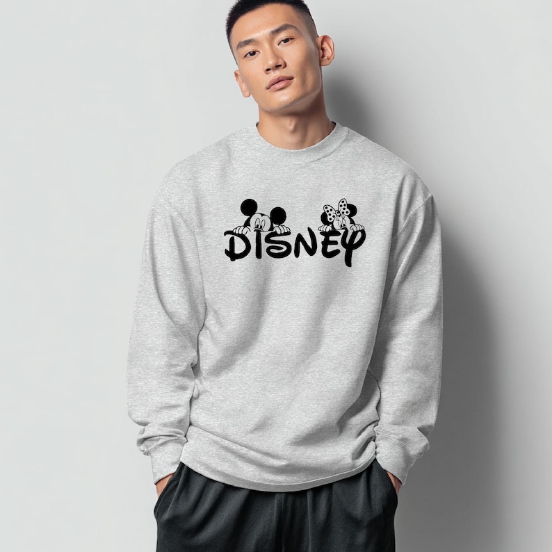 Pu&ograve; includere: Una felpa grigio chiaro con la scritta "DISNEY" in nero, con le sagome di Topolino e Minnie Mouse sopra il testo. La felpa ha un girocollo e maniche lunghe.