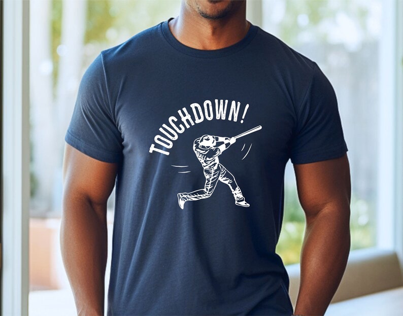 May include: A navy blue t-shirt with a white graphic of a baseball player swinging a bat and the text "TOUCHDOWN!"