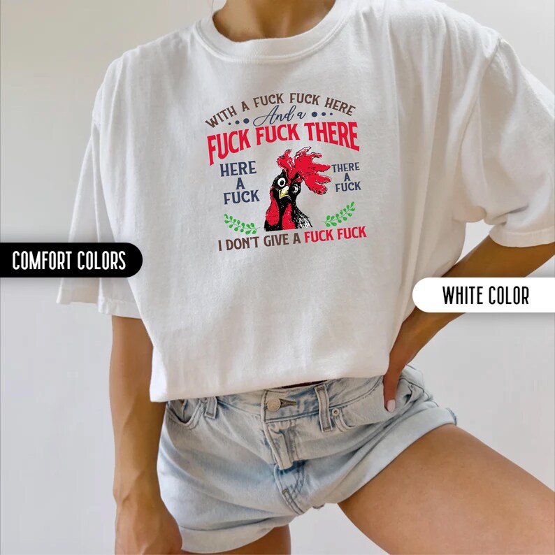 May include: White t-shirt with a graphic of a rooster and the text "WITH A FUCK FUCK HERE, And a FUCK FUCK THERE, HERE A FUCK, THERE A FUCK, I DON'T GIVE A FUCK FUCK". The shirt has short sleeves and is labeled "COMFORT COLORS" and "WHITE COLOR".