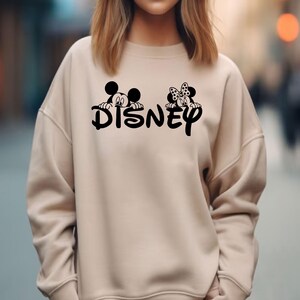 Pu&ograve; includere: Felpa beige con la scritta "Disney" in nero e grafica di Topolino e Minnie. La felpa ha girocollo e maniche lunghe. Il disegno &egrave; centrato sul davanti del capo.