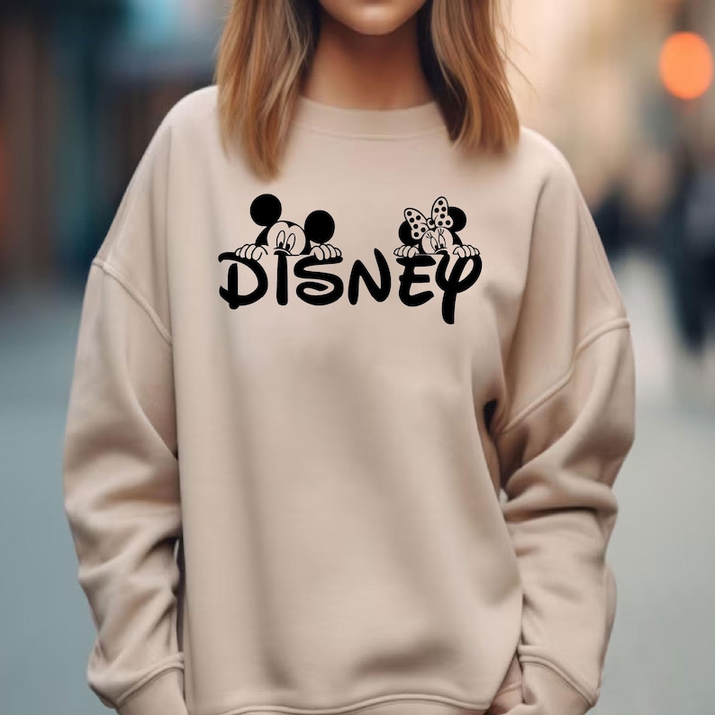 Pu&ograve; includere: Felpa beige con la scritta "Disney" in nero e grafica di Topolino e Minnie. La felpa ha girocollo e maniche lunghe. Il disegno &egrave; centrato sul davanti del capo.