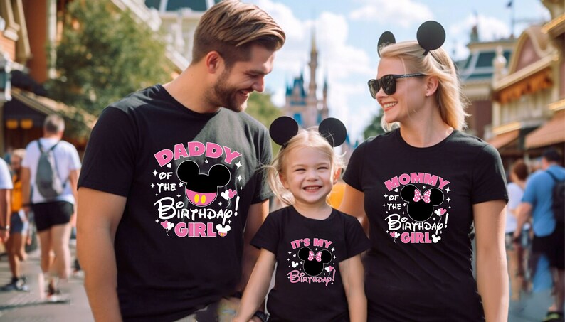 Puede incluir: Familia con camisetas negras a juego con dise&ntilde;os de Mickey Mouse. Las camisetas dicen "Daddy of the Birthday Girl", "Mommy of the Birthday Girl" e "It's My Birthday!" en texto rosa y blanco. Todos llevan orejas de rat&oacute;n.