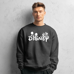 Pu&ograve; includere: Felpa grigio scuro con la scritta "Disney" bianca e le sagome di Topolino e Minnie Mouse sopra. La felpa &egrave; a girocollo.