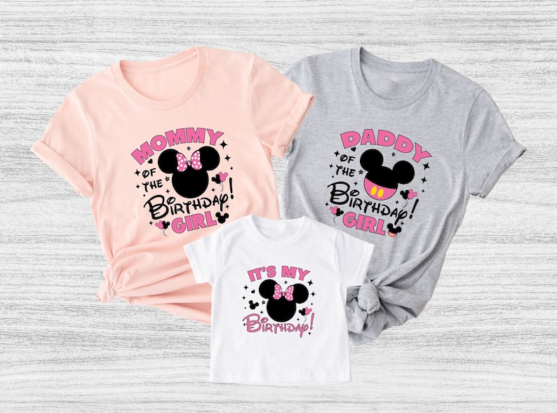 Puede incluir: Tres camisetas con dise&ntilde;os de cumplea&ntilde;os. Las camisetas son rosas, grises y blancas. Cada camiseta presenta un gr&aacute;fico de la cabeza de Minnie Mouse y las frases "Mommy of the Birthday Girl", "Daddy of the Birthday Girl" y "It's My Birthday!"