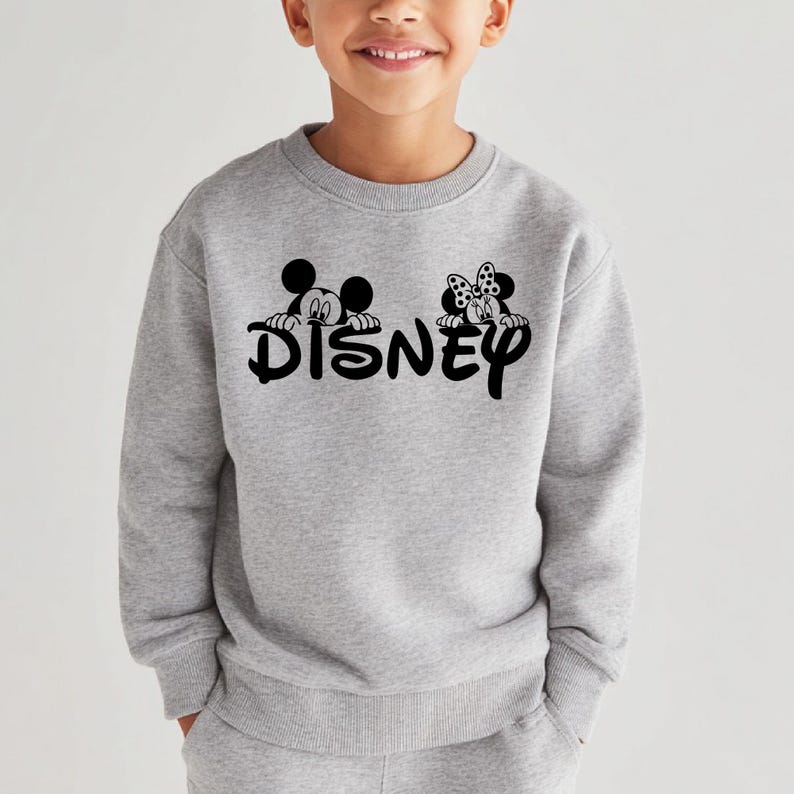 Pu&ograve; includere: Una felpa grigio chiaro con la scritta "DISNEY" in nero, con grafiche di Topolino e Minnie Mouse sopra le lettere. La felpa &egrave; a girocollo e sembra essere realizzata in un materiale morbido.