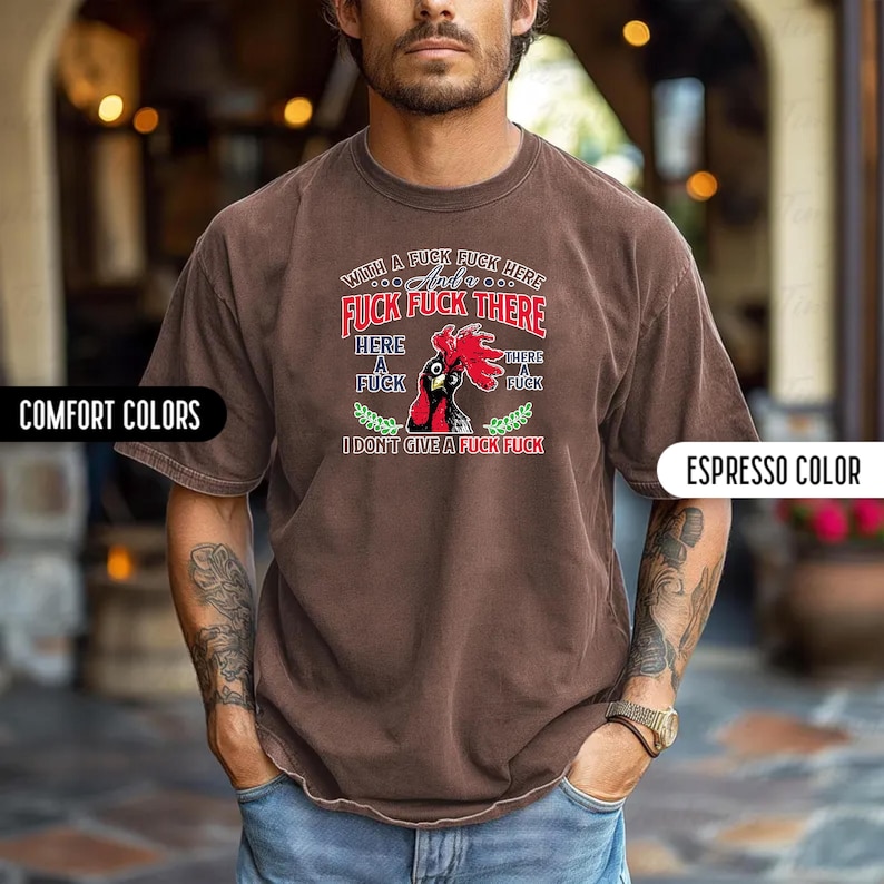May include: Espresso-colored t-shirt with a graphic of a rooster and the text "WITH A FUCK FUCK HERE, FUCK FUCK THERE, I DON'T GIVE A FUCK FUCK". The shirt is part of the "Comfort Colors" collection.