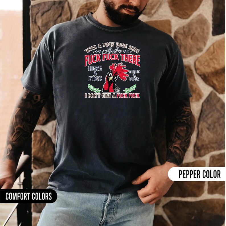May include: A dark gray t-shirt with a graphic featuring a rooster and the text "WITH A FUCK FUCK HERE AND FUCK FUCK THERE, HERE A FUCK, THERE A FUCK, I DON'T GIVE A FUCK FUCK." The shirt is labeled "PEPPER COLOR" and "COMFORT COLORS."