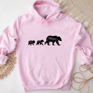 May include: Pink hooded sweatshirt with a black silhouette of three bears. The largest bear says "Mama" and the two smaller bears say "Ryan" and "Mason".