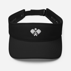 May include: Black visor with a white embroidered design of two pickleball paddles and a ball.