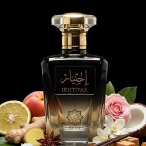 May include: A black perfume bottle with a gold cap and the word "IKHTIYAR" in gold lettering. The bottle is surrounded by a peach, lemon slice, ginger, star anise, rose, coconut, and vanilla beans. The perfume bottle has the word "ABYAT" at the bottom.