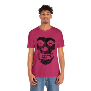 May include: A pink t-shirt with a black skull graphic. The skull has a distressed look and is centered on the shirt.