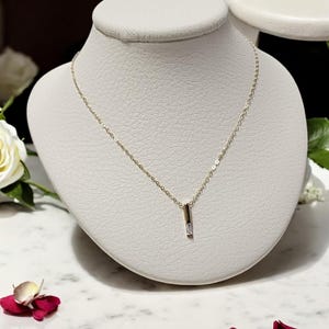 May include: A gold chain necklace with a small, clear, rectangular pendant.