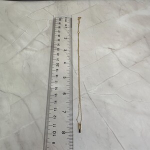 May include: A gold chain necklace with a small black stone pendant. The necklace is about 18 inches long.