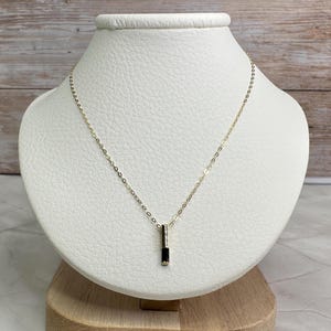 May include: A gold chain necklace with a black rectangular pendant.