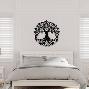 May include: Black metal wall art featuring a tree of life design with detailed branches and roots. The art is displayed on a white wall above a bed with white bedding.