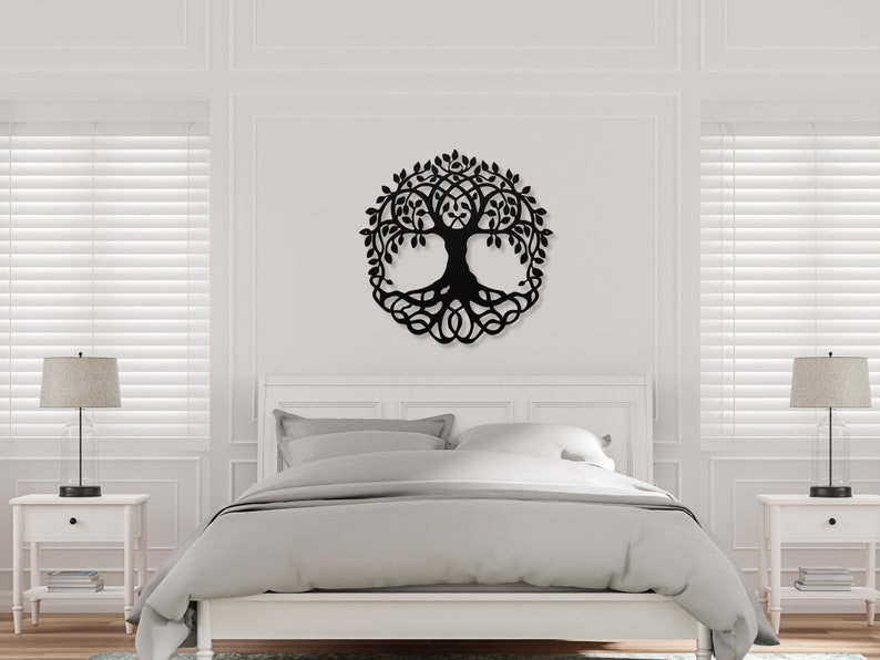 May include: Black metal wall art featuring a tree of life design with detailed branches and roots. The art is displayed on a white wall above a bed with white bedding.