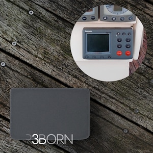 May include: A grey rectangular speaker with the text "3BORN" printed on the front. The speaker is sitting on a wooden surface.