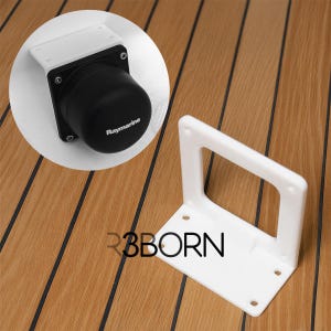 Puede incluir: Un soporte blanco con un asa rectangular y orificios de montaje, junto a un dispositivo Raymarine negro con una placa de montaje blanca. La imagen está sobre una superficie de vetas de madera, con el texto "R3BORN" visible.