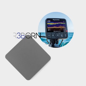 May include: A grey, diamond-shaped object with rounded corners is in the foreground. In the background, a Raymarine Dragonfly-5 fish finder displays colorful sonar data. The screen shows a blue ocean background.
