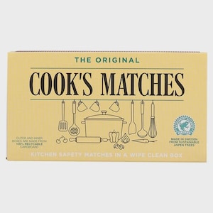 May include: A rectangular yellow box of The Original Cook's Matches featuring black line art of kitchen utensils and a pot. Text includes 'The Original Cook's Matches', 'Made in Sweden from sustainable aspen trees', and 'Kitchen safety matches'.