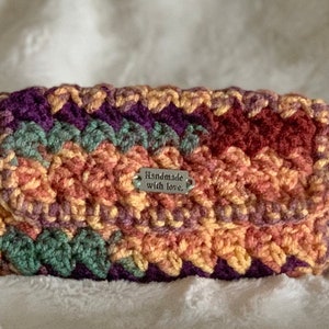 May include: A multi-colored crocheted wallet with a silver tag that reads "Handmade with love."