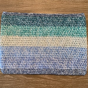 Peut inclure: Un article rectangulaire fait à la main au crochet avec des rayures horizontales de différentes nuances de bleu et de vert. Le bord supérieur est bleu foncé, passant à des bleus et verts plus clairs, et se terminant par une base bleu clair. L'article est probablement une écharpe ou un col.