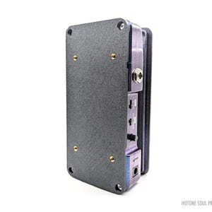 May include: A black and gray Hotone Soul Press II guitar effects pedal. The pedal has a textured surface with gold-colored screws and various input/output jacks. The text "HOTONE SOUL PRESS II" is visible.