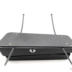 May include: Black Cry Baby guitar pedal with two black cable ties attached to the top. The pedal has a black and white stripe around the edge and a silver input jack.