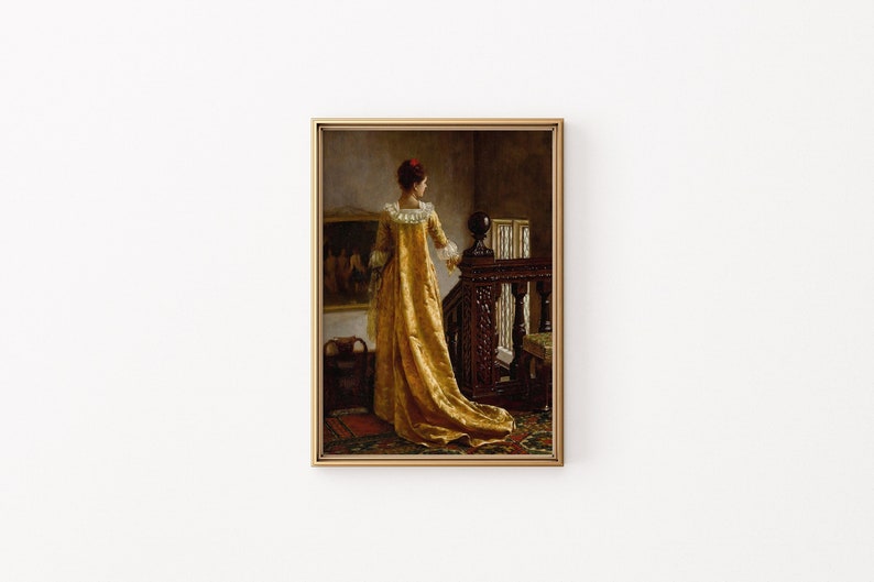 Op de afbeelding: Een ingelijst vintage schilderij toont een vrouw in een lange, gouden jurk die bij een donkere houten trap staat. Het kunstwerk heeft een warm kleurenpalet, met de jurk van de vrouw en de omliggende kamer badend in zacht licht.