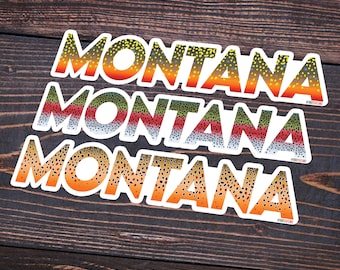 Könnte beinhalten: Drei Aufkleber mit dem Wort "MONTANA" in fetter, weißer Schrift auf einem Hintergrund mit Forellenmuster. Das Forellenmuster ist eine Mischung aus Braun, Orange, Gelb, Grün und Grau.