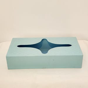 Peut inclure: Un boîtier à mouchoirs rectangulaire bleu clair doté d'une ouverture centrale en forme d'étoile. La surface supérieure est ornée d'un motif en grille de losanges subtilement gaufré qui s'étend sur les quatre coins autour de la découpe.