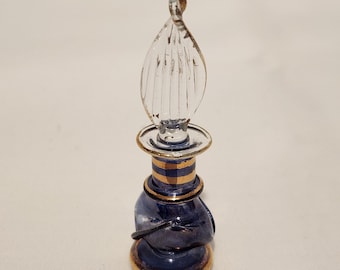 Frasco de perfume vintage en miniatura de vidrio soplado con tapón transparente retorcido, detalles en azul, morado y dorado, de aproximadamente 7 cm de altura.