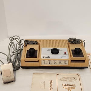 May include: A vintage Granada 4 Electronic TV Sport Games console with two controllers and a manual. The console is beige and brown with black knobs and buttons. The manual is off-white with the Granada logo and game details.