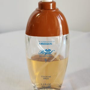 May include: A clear glass bottle of cologne spray with a brown cap. The bottle is labeled "Royal Selections No. 7" and says "Our alternative to Obsession" and "Cologne Spray 3.3 fl. oz. 100 ml e Made in USA."