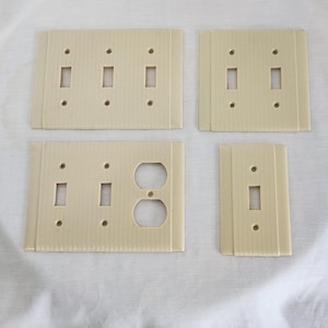 Uniline Manufacturing vägguttagsplattor i bakelitplast, ribbad, strömlinjeformad design, elfenben, USA, 3 2 & 1 vippkontakt, 2 vippkontakter med 2 uttag