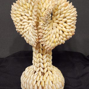 Puede incluir: Una escultura decorativa hecha completamente de pequeñas conchas blancas. Las conchas están dispuestas en espiral, creando un diseño único y llamativo.