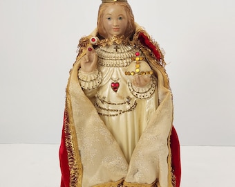 Figura religiosa del Niño Jesús de Praga de la década de 1960, de 33 cm de altura, realizada en yeso/corcha de tiza. Incluye túnica de tela elaborada y joyas originales. Aproximadamente 33 cm de altura.