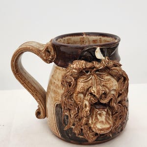 Vintage 1980-tals John Coiner keramikmugg med ett fult ansikte, handgjord stengods, konstnärsmärkt, ca 13 cm hög, 14 cm bred
